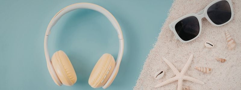 Headphones and sunglasses on the beach sand.