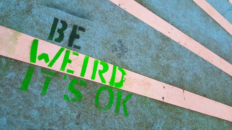 Chalk writing of "Be weird It's Okay" on an Odense street.
