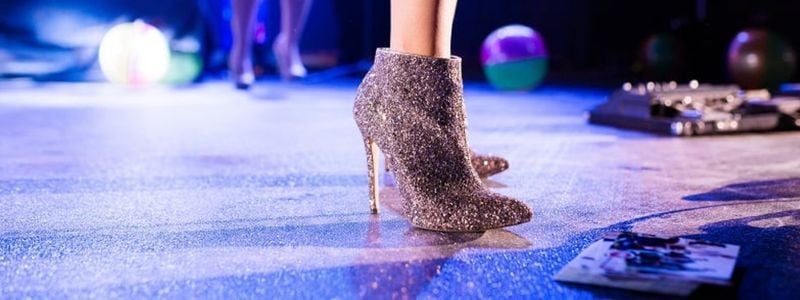 Glittery stilettos and bare legs on a stage.