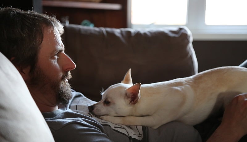 A guy on the couch with his dog.