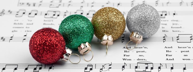 Four Christmas ornaments on sheet music.