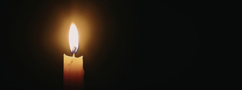 A lit candle with a dark background.