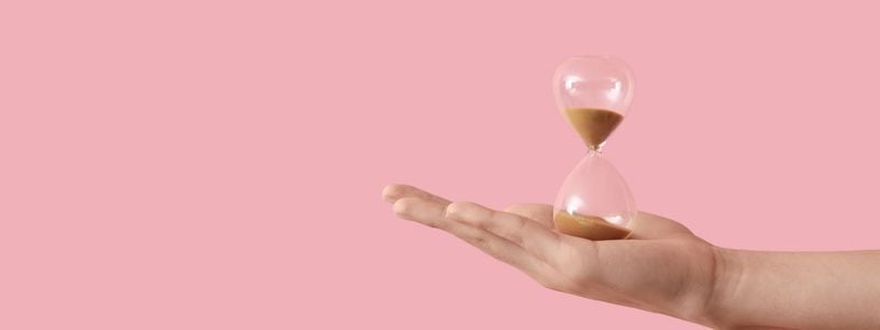 An hourglass with a light pink background.