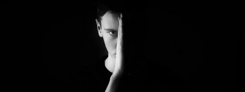 Half of a man's face in the darkness.