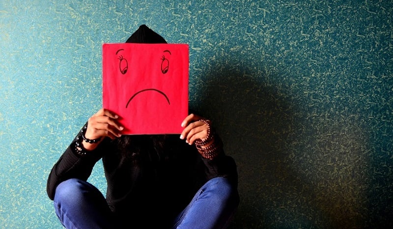 A man holding an unhappy face sign.