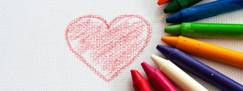 A heart drawing surrounded by colorful crayons.