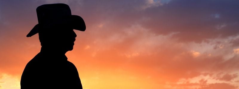 A cowboy silhouette in front of a sunset.
