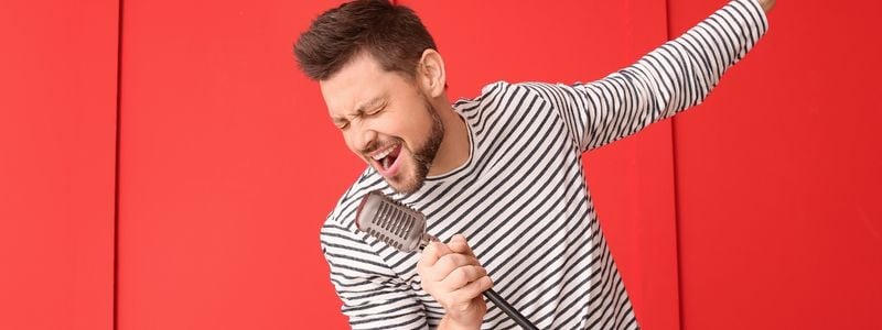 A man singing with a red background.