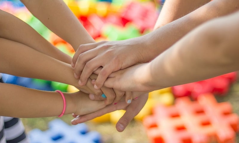 Four teens holding hands in friendship.