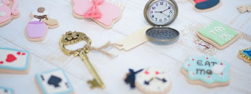 Alice in Wonderland style cookies, clocks and keys on a table.