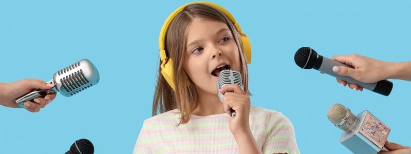 A young girl surrounded by microphones.