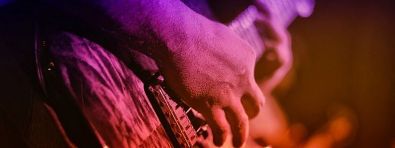 Neon washed hands playing a rock guitar.