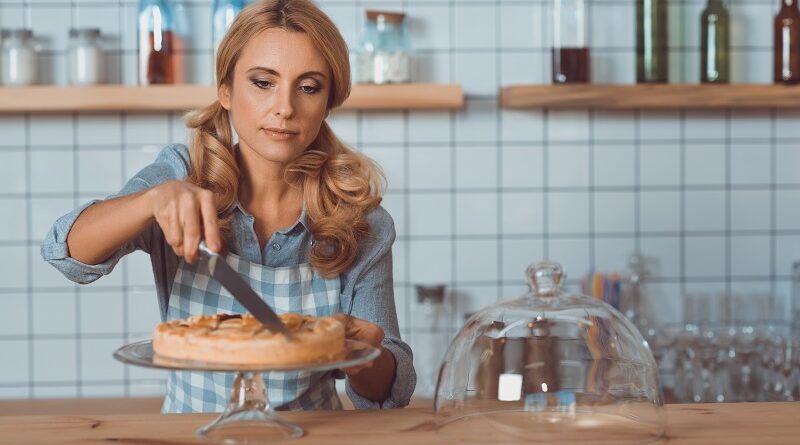 A waitress cutting a pie.