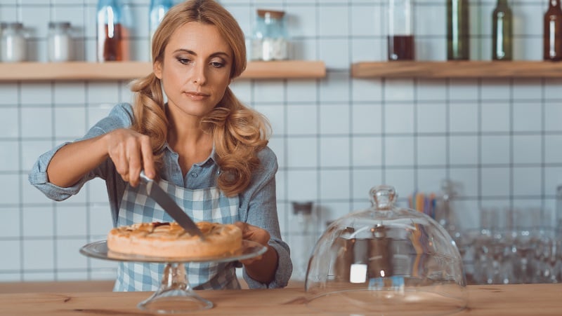A waitress cutting a pie.