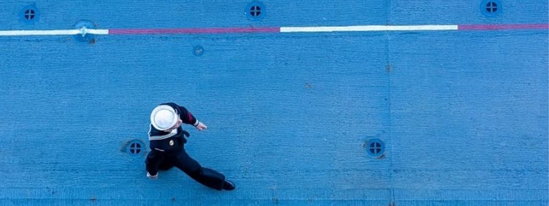 A sailor walking on a blue street.