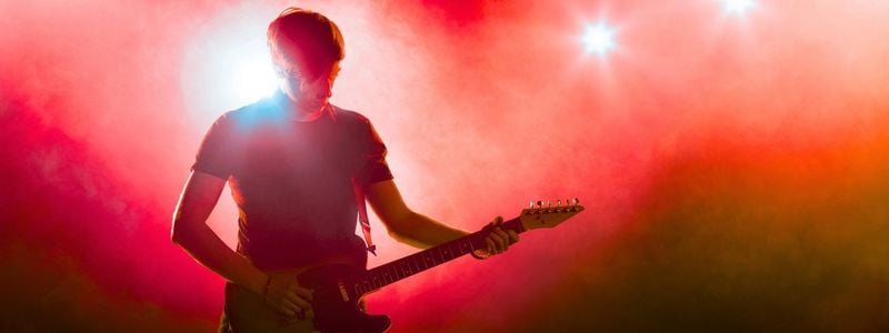 A rock guitarist on a red stage.