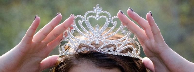 A girl putting on a tiara.