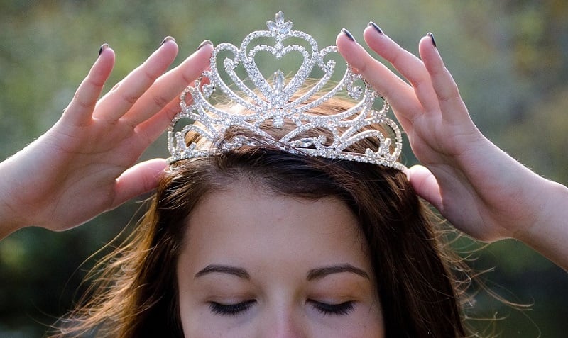 A girl putting on a tiara.