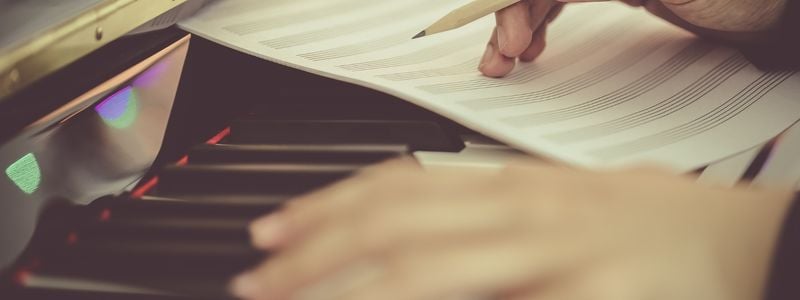 Hands composing at the piano.