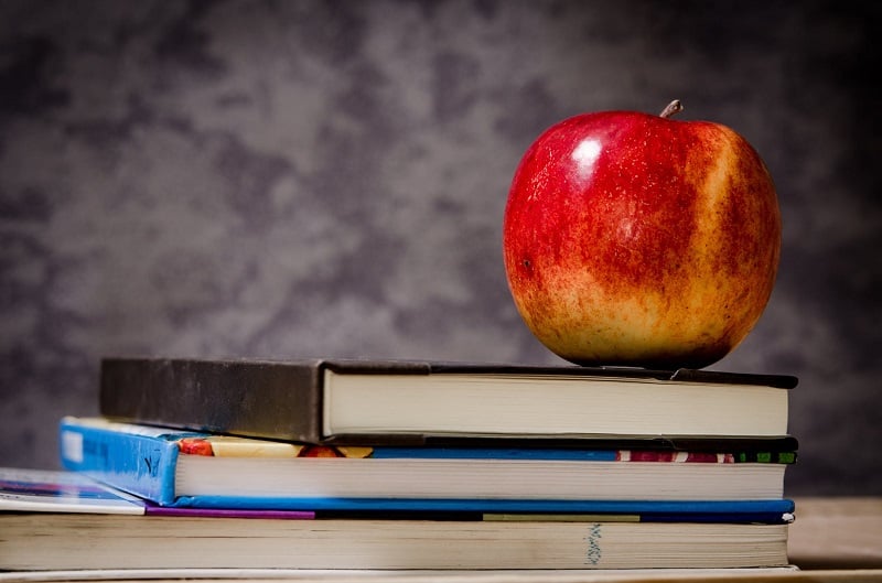 An apple on top of school books.