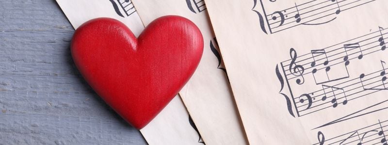 A wooden heart on top of sheet music.