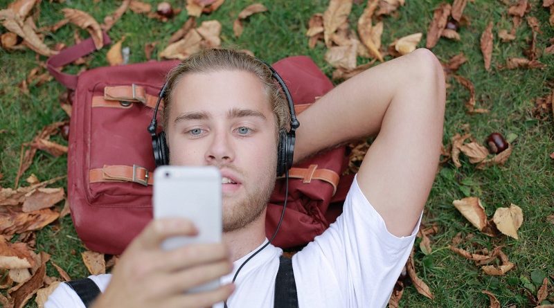 A man listening to music on the grass.