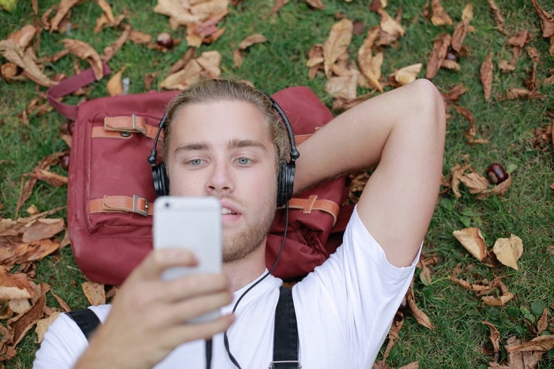 A man listening to music on the grass.