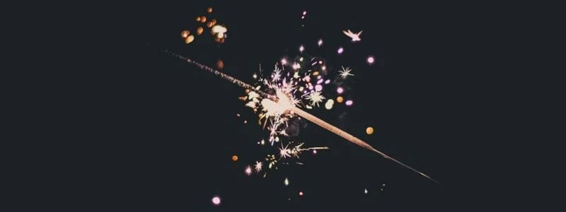 A lit sparkler on a dark background.