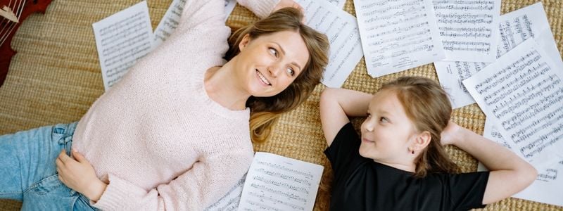 A mother and daughter lying on sheet music.
