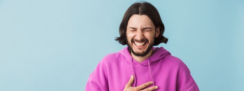 A man laughing with a blue background.