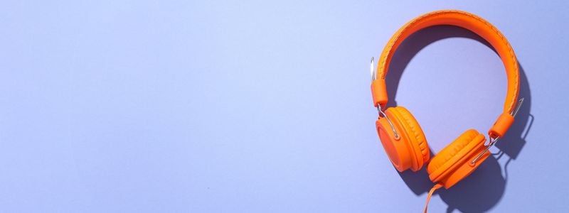 Big orange headphones on a purple background.