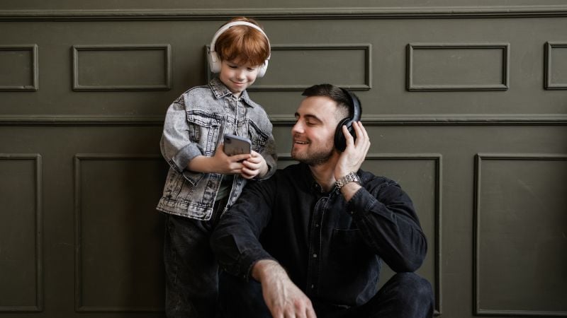 A dad and son listening to headphones.