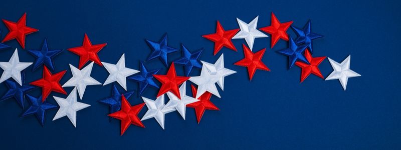 Red white and blue fabric stars scattered on a blue background.