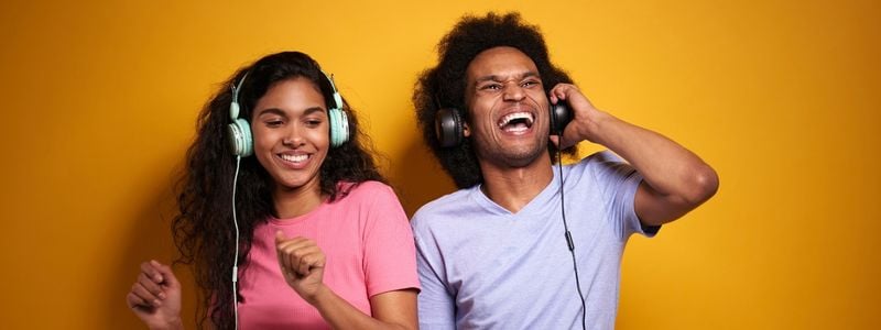 A man and woman listening to headphones and smiling.
