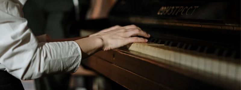 The hands of a pianist at an older piano.