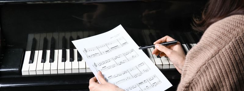 Someone noting sheet music at a piano.