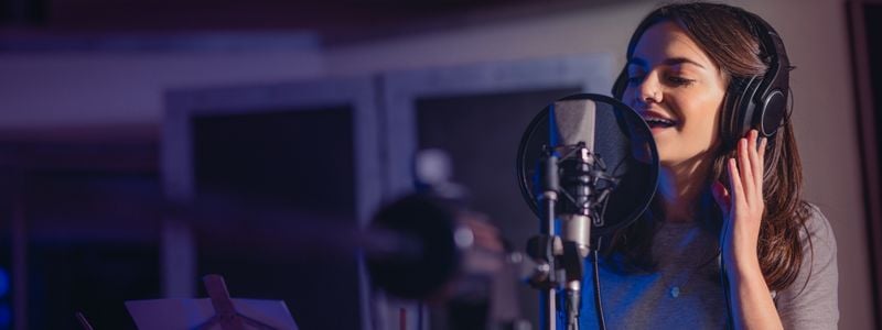 A woman singing in a studio with headphones on.