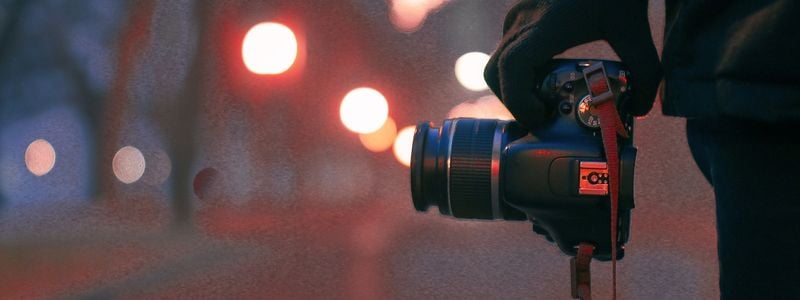 A photographer's camera in hand at night.