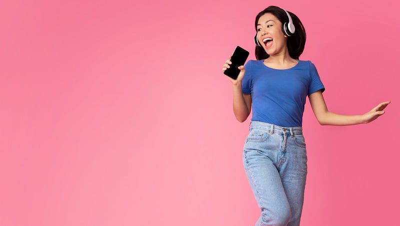 A happy woman singing with her phone.
