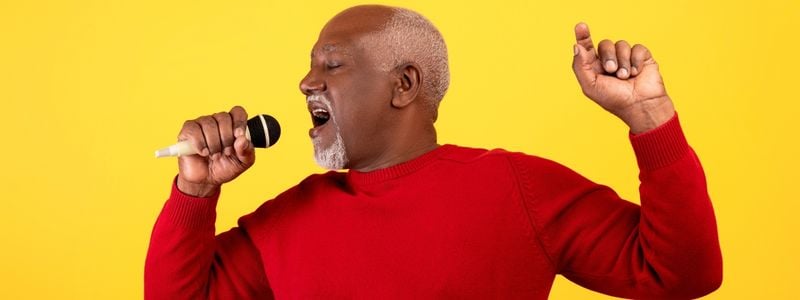 An older man singing into a microphone.