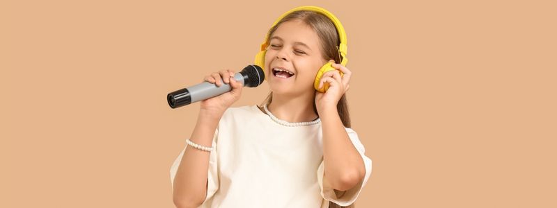 A tween singer with a microphone and headphones.