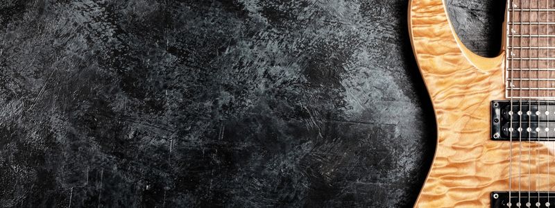 Part of an electric guitar on a black background.