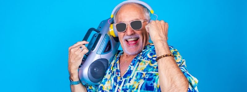 A man with sunglasses, headphones, a colorful shirt, and a boombox.