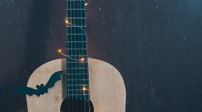 A guitar decorated with a Halloween bat and lights.