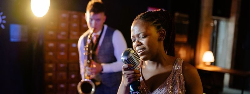 A woman singing a song with a saxophonist on stage.