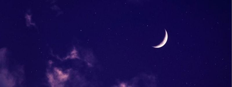 A crescent moon in a purple night sky.