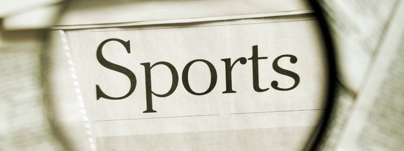 The newspaper sports section under a magnifying glass.