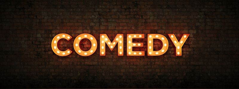 The word "comedy" written with a stage light style sign.