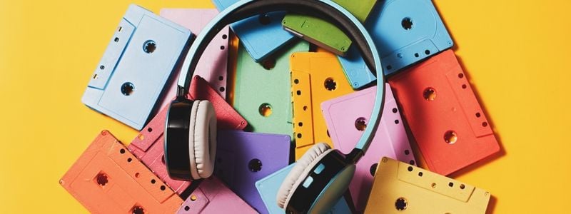 Headphones lying on colorful 1970s style cassette tapes.