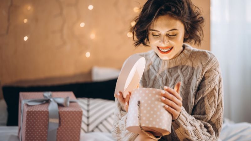 A woman excitedly opening a gift.